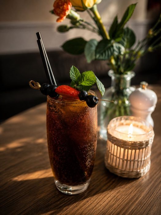 Cola cocktail garnished with berries and mint at Musti's Grill & Bistro